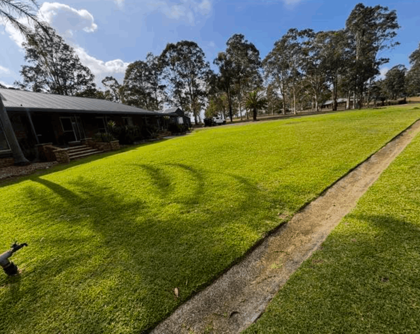 Freshly mown lawn with crisp edges along a timber retaining wall in Greta NSW